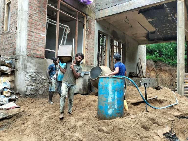 Workers on a building site with a portable concrete mixer