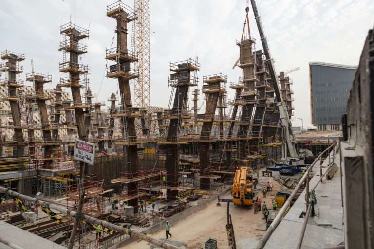 Busy commercial construction site with steel framework and cranes